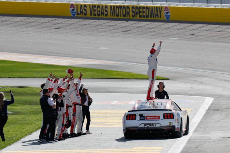 Josh Berry standing on top of his car with his crew cheering him on behind him