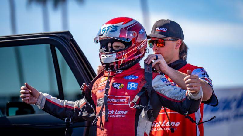 Tasca having a team member help suit him up