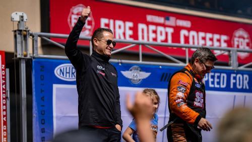 Bob Tasca standing on the award stage with his fist in the air