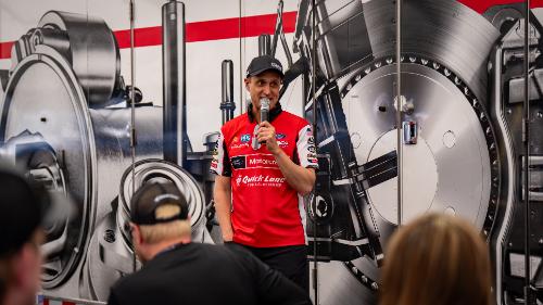 Bob Tasca holding a microphone standing in front of a small crowd