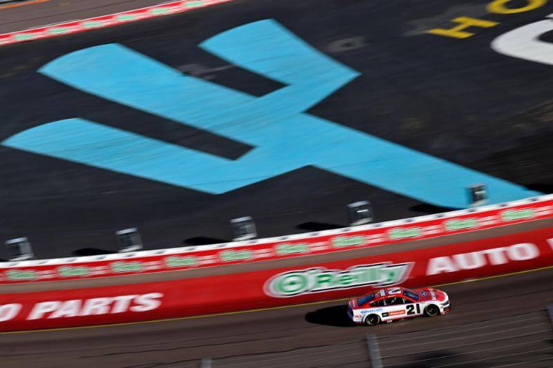 Zoomed out shot of the number 21 car on track with a blue teal cacti in the background