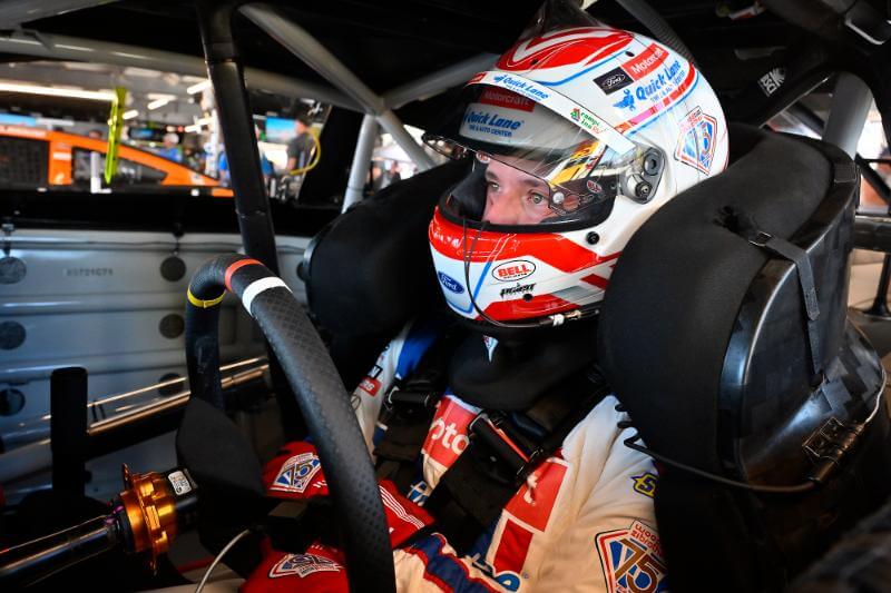Josh Barry inside the car with his helmet and suit on buckled up