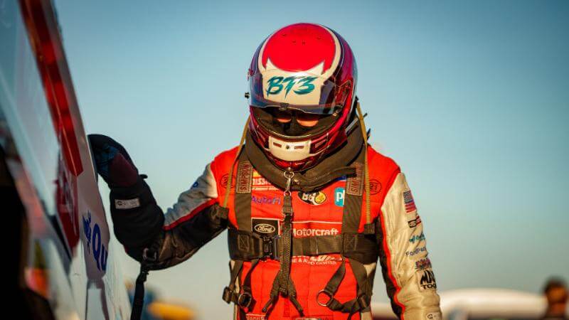 Dramatic shot of Tasca in all gear and hand on the side of the car