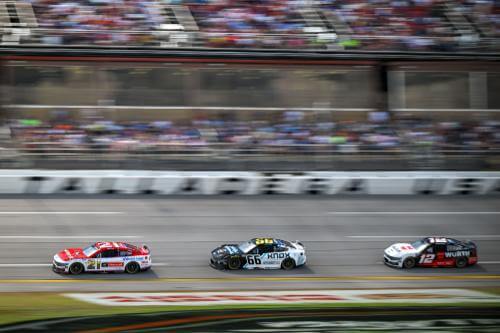 Far out shot of 3 NASCAR drivers coming around the track