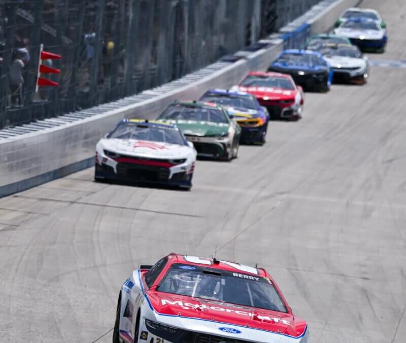 Portrait view of number 21 NASCAR in the front of a line of cars